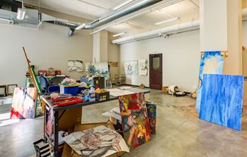 a room with paintings on the walls and a table with art supplies on it